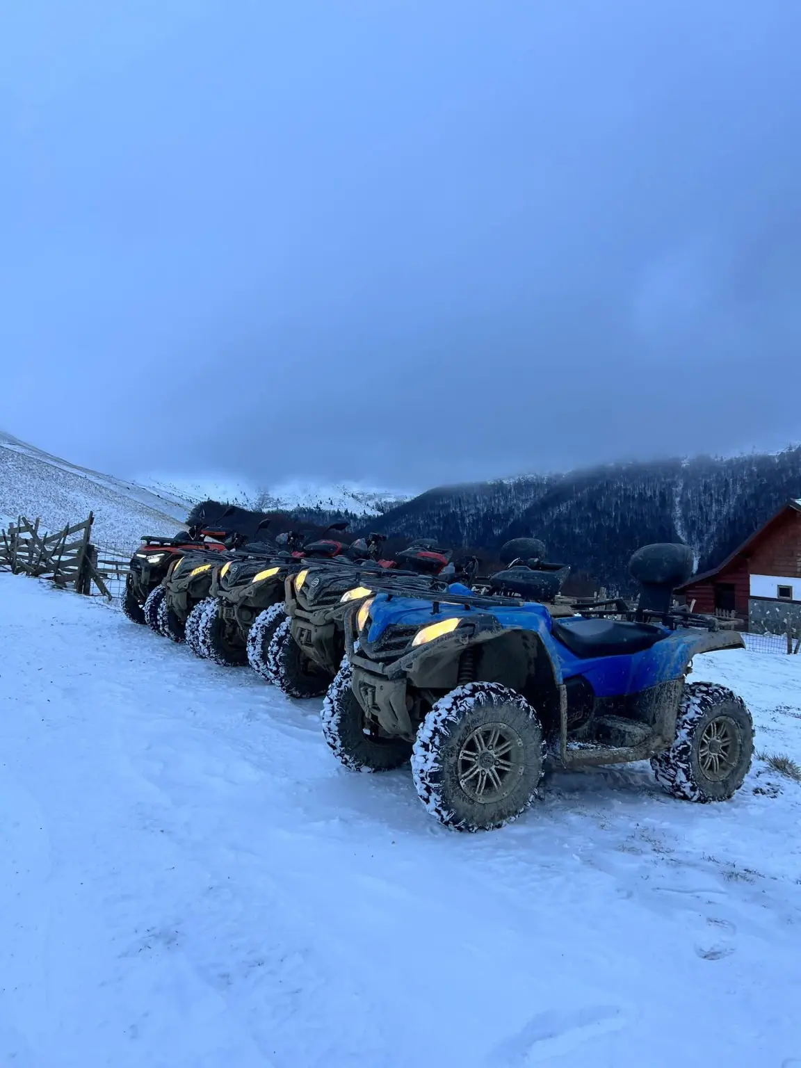 Flotă de ATV-uri CFMoto gri și albastre, aliniată pe traseu înzăpezit